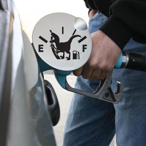 May include: A blue gas pump nozzle with a black dinosaur silhouette on the fuel gauge. The gauge reads "E" for empty and "F" for full.