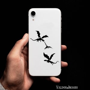 May include: A white iPhone case with a black silhouette of two dragons. The dragons are facing each other, one is flying and the other is on the ground.