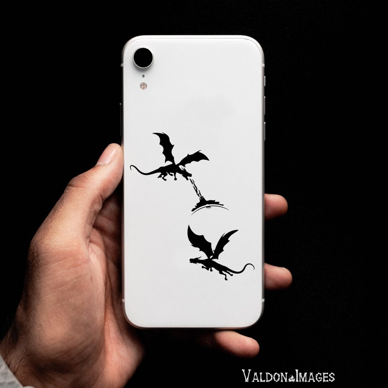 May include: A white iPhone case with a black silhouette of two dragons. The dragons are facing each other, one is flying and the other is on the ground.