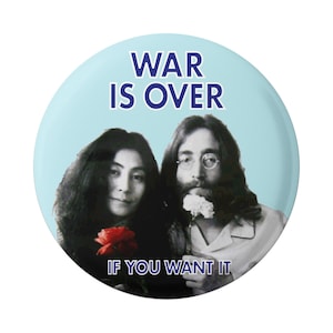以下が含まれることがあります： ジョン・レノンとオノ・ヨーコの白黒写真が描かれた青いボタン。ボタンには「WAR IS OVER IF YOU WANT IT」という文字が青色で印刷されています。