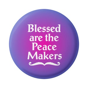 May include: A round, purple button with the words "Blessed are the Peace Makers" in white, along with a white mustache graphic. The button has a gradient effect, transitioning from purple to pink.