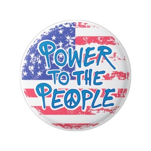 May include: A white button with a distressed American flag design and the text "POWER TO THE PEOPLE" in blue with a peace symbol.