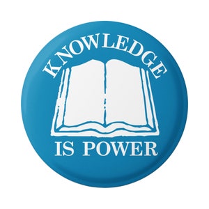 Puede incluir: Un botón redondo azul con el texto "Knowledge is Power" en blanco. Un contorno blanco de un libro abierto está en el centro del botón.