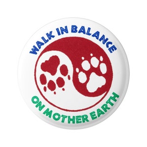 May include: A white button with a red and white yin yang symbol. The symbol has a paw print on each side. The text "Walk in Balance on Mother Earth" is written around the symbol in blue and green.