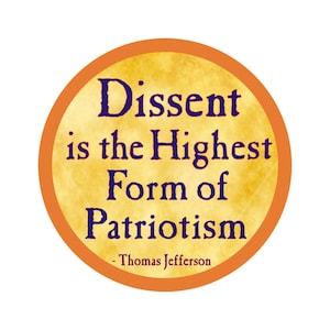 Può includere: Un cartello rotondo con bordo arancione, sfondo giallo e il testo "Dissent is the Highest Form of Patriotism - Thomas Jefferson" in blu scuro.