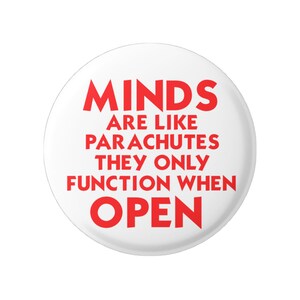 以下が含まれることがあります： 「MINDS ARE LIKE PARACHUTES THEY ONLY FUNCTION WHEN OPEN」と赤い文字で書かれた白いボタン。