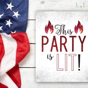 May include: A white sign with red glitter text that reads "This Party is LIT!" with two red flames on either side of the text. The sign is on a white wood background.