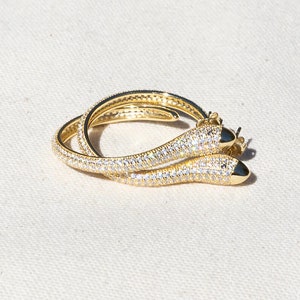 May include: A pair of gold hoop earrings with a pave setting of clear cubic zirconia stones.