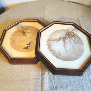 May include: Two octagonal framed prints with watercolor paintings of birds and flowers. The frames are dark brown wood with a gold inner border.