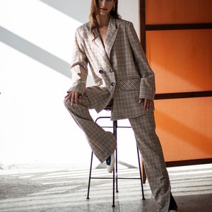 Two-piece pants suit. The pants boasts high side slits, and the blazer comes with a double-breasted closure a classic lapper collar.