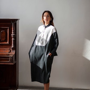 Oversized wool dress with Dolman sleeves and vertical stripes. The dress also features French cuff and  a calf-length hem.