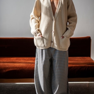 Raglan sleeve Merino wool sweater with functional front pockets paired with a pair of relaxed-fit plaid trousers.