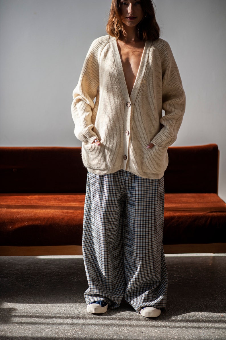 Raglan sleeve Merino wool sweater with functional front pockets paired with a pair of relaxed-fit plaid trousers.