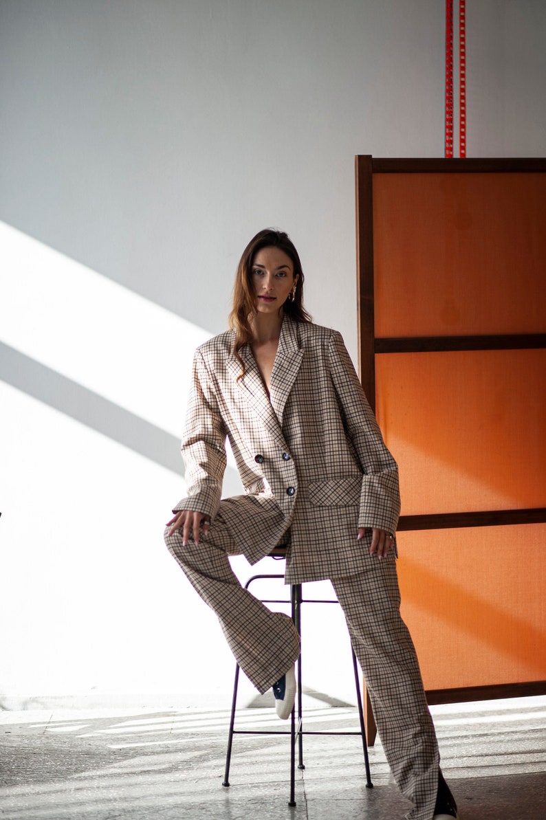 Two-piece pants suit. The pants boasts high side slits, and the blazer comes with a double-breasted closure a classic lapper collar.