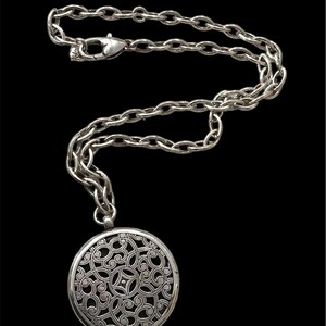 May include: Silver-toned necklace with a large, round pendant featuring an intricate openwork design. The pendant hangs from a chunky chain with a lobster clasp closure. The necklace is displayed against a black background.