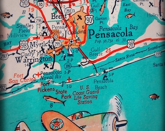 May include: A vintage map of Pensacola, Florida, with a red and white airplane flying over a turquoise blue body of water. The map shows the location of Pensacola Bay, Pensacola Beach, and the U.S. Coast Guard Life Saving Station. The airplane has the letters "U.S.O" on the side.