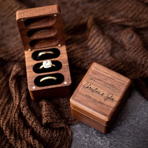 May include: A wooden ring box with a hinged lid and three compartments for rings. The box is engraved with the names "Christine & Tyler" and the date "April 24, 2021".