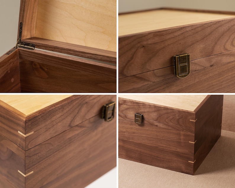 May include: A rectangular wooden box crafted from dark brown walnut wood with a lighter wood lid. The box features visible corner joinery with light-colored wood splines, a metal latch closure, and metal hinges on the interior lid attachment.
