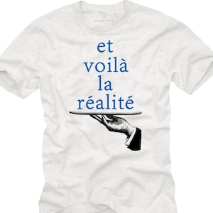 Könnte beinhalten: Weißes T-Shirt mit dem blauen Text "et voilà la réalité". Das Design zeigt eine Schwarz-Weiß-Illustration einer Hand, die ein Tablett hält. Das Shirt hat einen Rundhalsausschnitt und kurze Ärmel.