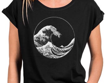 Könnte beinhalten: Schwarzes T-Shirt mit einer weißen Grafik einer großen Meereswelle in einem Kreis. Das Wellenmuster ist von traditioneller japanischer Kunst inspiriert. Das T-Shirt hat kurze Ärmel und einen Rundhalsausschnitt.