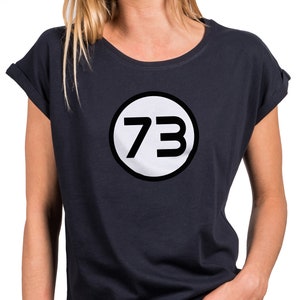 Könnte beinhalten: Ein marineblaues T-Shirt mit einem weißen Kreis, der die Zahl 73 in Schwarz enthält.