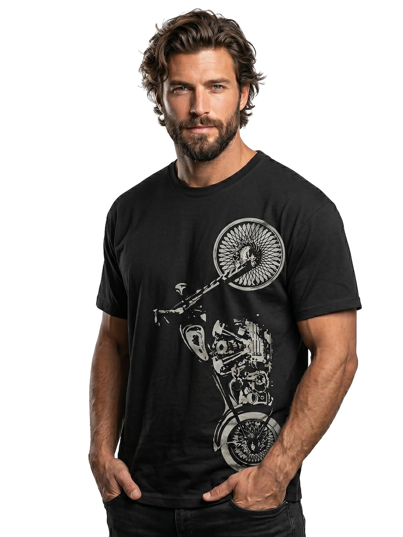 以下が含まれることがあります： 黒いTシャツに銀色のオートバイのグラフィック。デザインは、前輪、エンジン、その他の機械部品を示しています。Tシャツはクルーネックです。