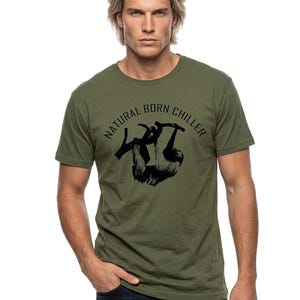 Pu&ograve; includere: T-shirt verde oliva con grafica nera di un bradipo appeso a un ramo. Il testo "NATURAL BORN CHILLER" &egrave; stampato sopra il bradipo. La maglietta &egrave; realizzata in materiale morbido.
