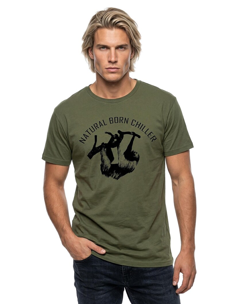 Pu&ograve; includere: T-shirt verde oliva con grafica nera di un bradipo appeso a un ramo. Il testo "NATURAL BORN CHILLER" &egrave; stampato sopra il bradipo. La maglietta &egrave; realizzata in materiale morbido.