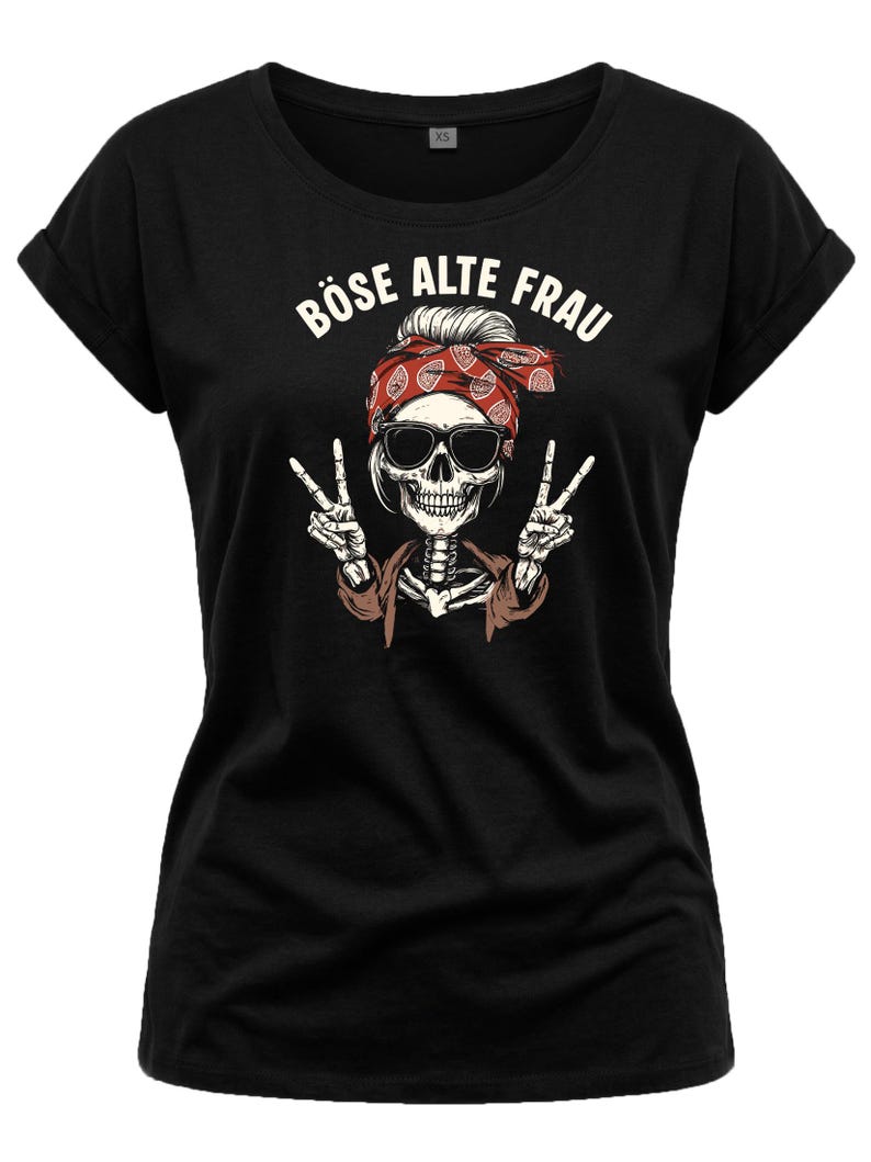 K&ouml;nnte beinhalten: Schwarzes T-Shirt mit einem Skelett, das eine Sonnenbrille und ein rotes Bandana tr&auml;gt und das Peace-Zeichen zeigt. Der Text "B&Ouml;SE ALTE FRAU" ist &uuml;ber dem Skelett aufgedruckt. Das T-Shirt hat hochgekrempelte &Auml;rmel.