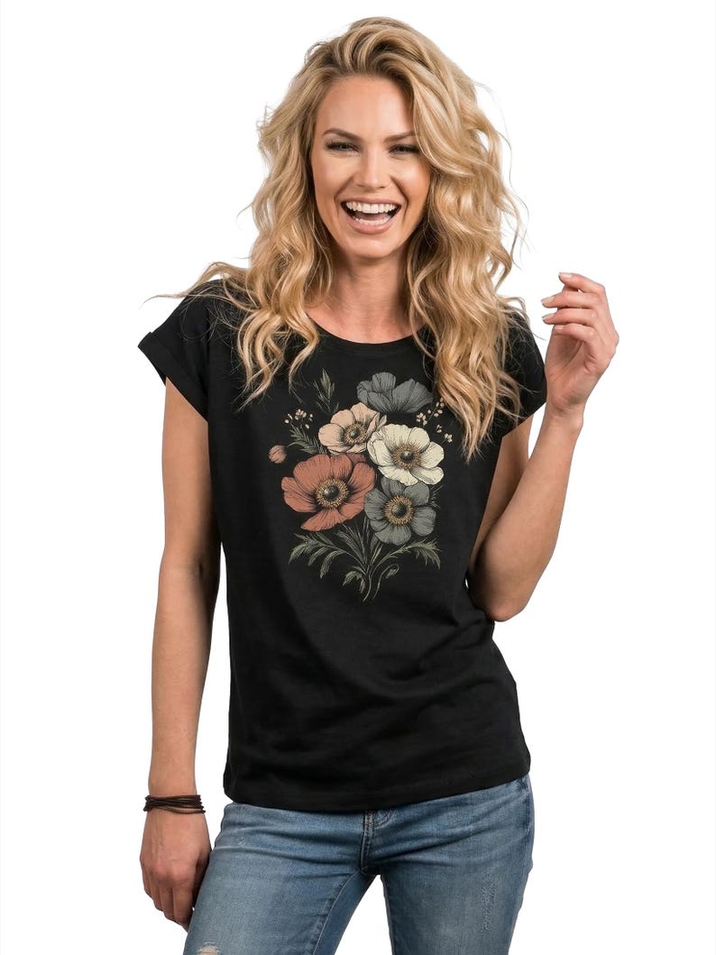 May include: Black t-shirt featuring a floral bouquet design in shades of peach, cream, and gray. The flowers are arranged with green leaves and stems. The shirt has a round neckline and short sleeves.