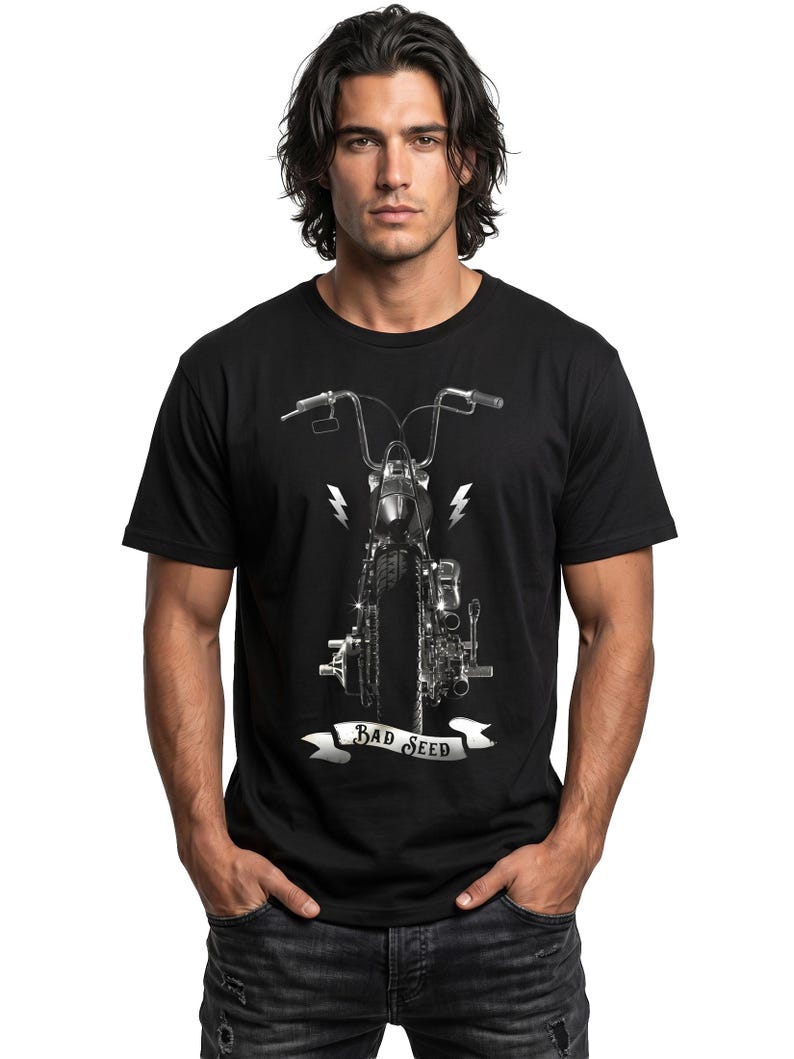 Puede incluir: Camiseta negra con un gr&aacute;fico de motocicleta en escala de grises, que muestra el manillar y rayos. El texto "BAD SEED" est&aacute; en una pancarta. El modelo lleva vaqueros azules. La imagen est&aacute; sobre un fondo blanco.