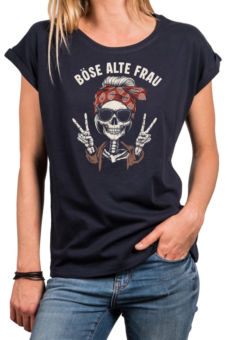 K&ouml;nnte beinhalten: Marineblaues T-Shirt mit einem Skelett-Motiv, das eine Sonnenbrille und ein rotes Bandana tr&auml;gt und Friedenszeichen zeigt. Der Text "B&Ouml;SE ALTE FRAU" ist &uuml;ber dem Motiv aufgedruckt. Das T-Shirt hat hochgekrempelte &Auml;rmel.