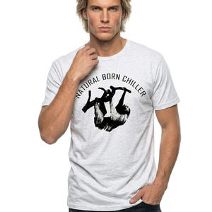 Pu&ograve; includere: T-shirt grigio chiaro con grafica nera di un bradipo appeso a un ramo e la scritta "NATURAL BORN CHILLER" in un cerchio. La maglietta &egrave; a girocollo.