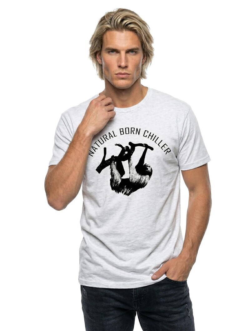 Pu&ograve; includere: T-shirt grigio chiaro con grafica nera di un bradipo appeso a un ramo e la scritta "NATURAL BORN CHILLER" in un cerchio. La maglietta &egrave; a girocollo.
