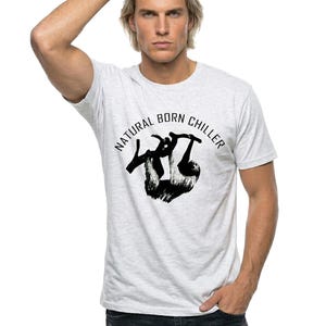 Pu&ograve; includere: T-shirt grigio chiaro con la scritta "NATURAL BORN CHILLER" e una grafica di bradipo nero. La maglietta &egrave; realizzata in materiale morbido, adatta per un abbigliamento casual.