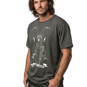 Puede incluir: Camiseta gris oscuro con un gr&aacute;fico de motocicleta, rayos y el texto "BAD SEED" en una pancarta. La camiseta tiene mangas cortas y cuello redondo.