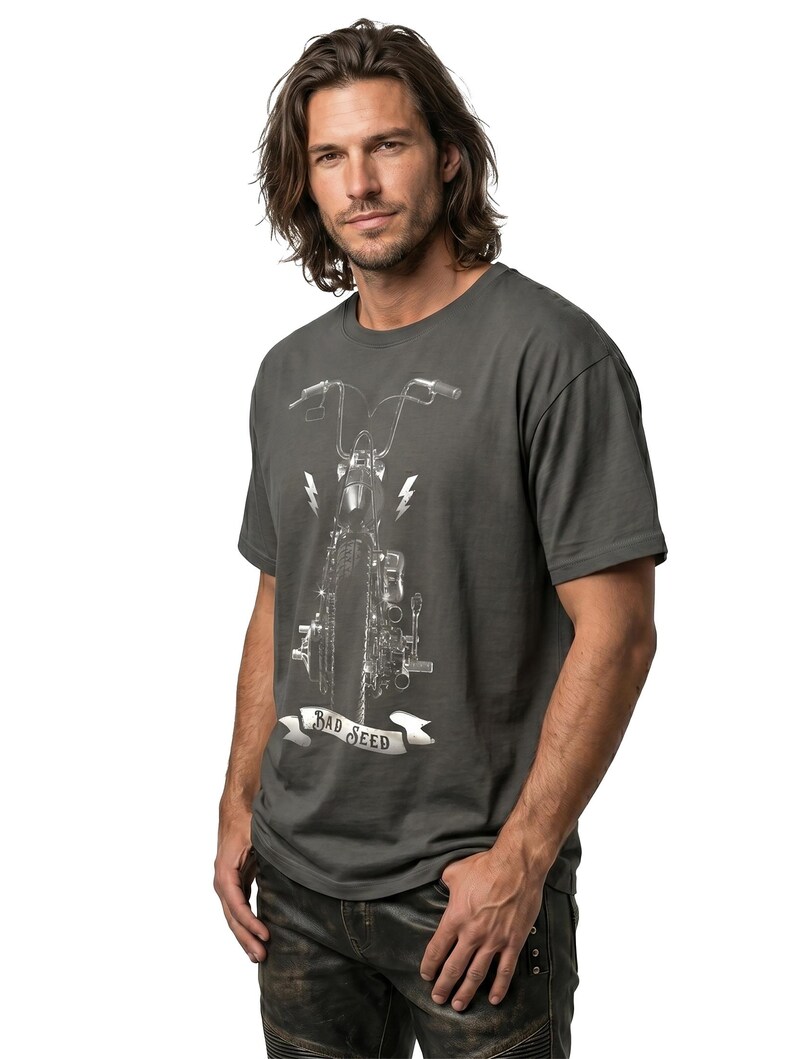 Puede incluir: Camiseta gris oscuro con un gr&aacute;fico de motocicleta, rayos y el texto "BAD SEED" en una pancarta. La camiseta tiene mangas cortas y cuello redondo.