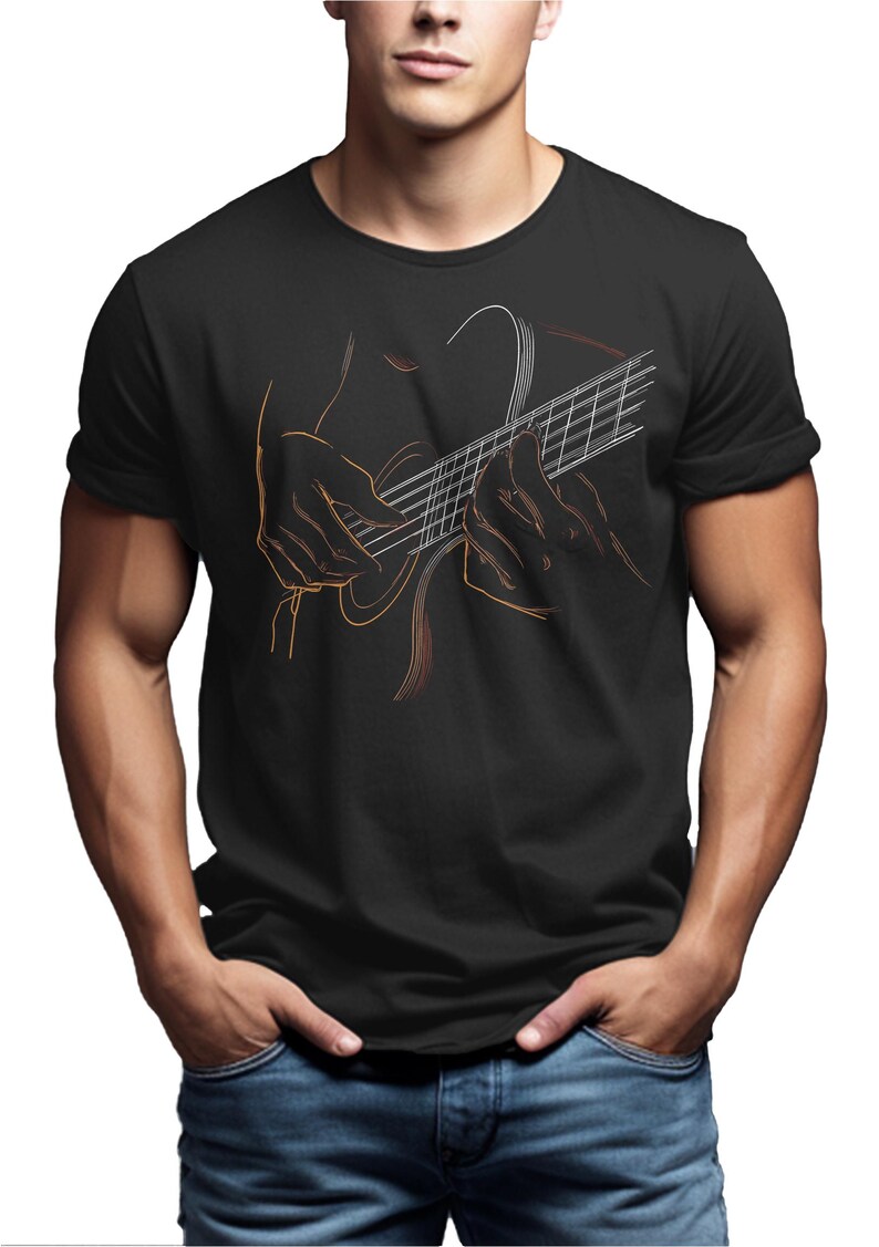 May include: Black t-shirt featuring a line art illustration of a person playing a guitar. The design uses orange and white lines to depict the guitar and the hands of the musician. The person is wearing blue jeans.