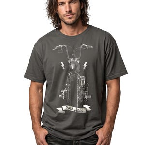 Puede incluir: Camiseta gris oscuro con un gr&aacute;fico detallado de motocicleta en blanco y negro. El dise&ntilde;o incluye rayos y una pancarta que dice "BAD SEED". La camiseta es de cuello redondo.