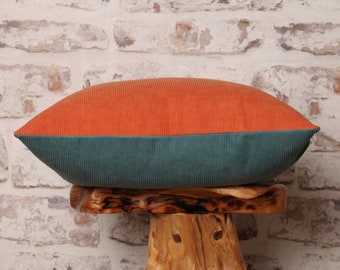May include: A rectangular pillow with a two-tone design. The top half is a bright orange corduroy and the bottom half is a teal green corduroy.