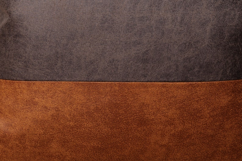 May include: Close-up of a brown and dark gray textured fabric. The fabric has a horizontal seam dividing the two colors.