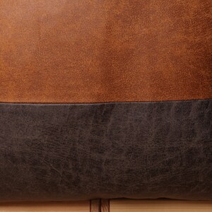 May include: A brown and black leather pillow with a textured surface.