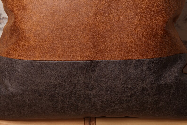 May include: A brown and black leather pillow with a textured surface.