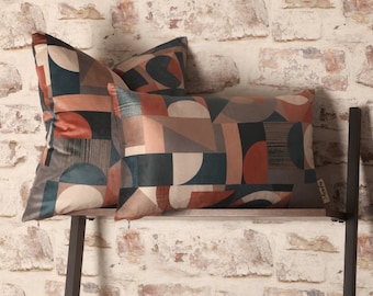 May include: Two decorative throw pillows with a geometric pattern in shades of brown, beige, teal, and red. The pillows are on a black metal shelf against a white brick wall.
