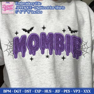May include: A light gray sweatshirt featuring a purple glittery applique design that spells the word MOMBIE in a dripping font. The design includes black embroidered spiderwebs, bats, stars, and a small spider, available in 5, 6, 7, and 8 inches.