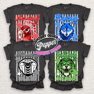 May include: Four charcoal gray t-shirts featuring graphic prints. Top left: red peacock with 'Amistad'. Top right: blue wolf with 'Reveur'. Bottom left: black and white cobra with 'Altruismo GIVERS'. Bottom right: green lion with 'Isibindi COURAGE'.