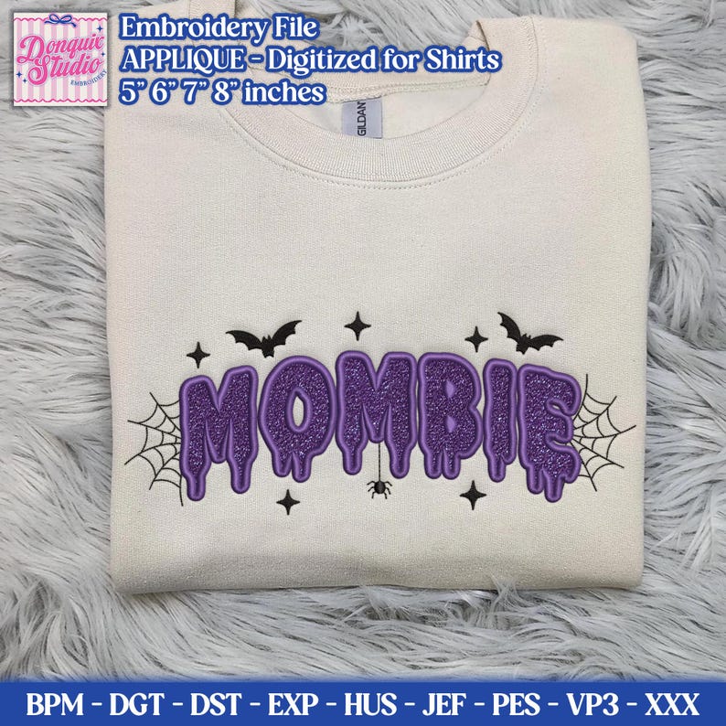 May include: A cream-colored crewneck sweatshirt featuring a purple glittery embroidered design that reads MOMBIE in a dripping font. The design includes black embroidered bats, spiderwebs, stars, and a small spider. Text at the top reads Embroidery File APPLIQUE - Digitized for Shirts 5 6 7 8 inches.