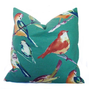 May include: Teal blue throw pillow with a watercolor pattern of colorful birds. The birds are painted in shades of orange, red, yellow, blue, and green.