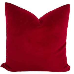 May include: A red velvet pillow with a smooth, soft texture. The pillow is square shaped and has a simple design.