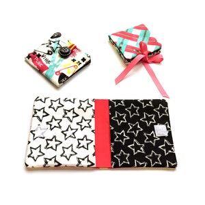 May include: Three small fabric covered notebooks with different patterns. One notebook has a black and white star pattern, another has a pink and white striped pattern, and the third has a colorful pattern with the word "punk" and a star.